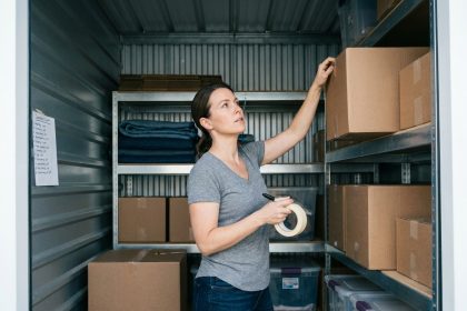 Femme organisant des cartons étiquetés sur des étagères métalliques dans un box de stockage
