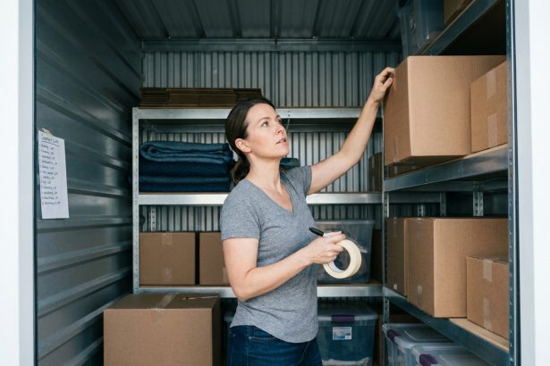 Femme organisant des cartons étiquetés sur des étagères métalliques dans un box de stockage